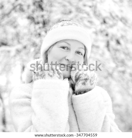 Winter portrait of a happy young woman in snowy landscape, black and white photo 
