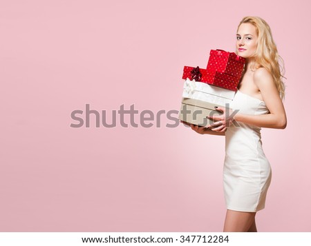 Portrait of a blond Christmas beauty holding gift boxes.