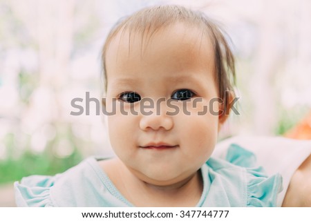 Close-up and soft focus picture of 1 year old baby who show a baby fat at her cheek and chin.