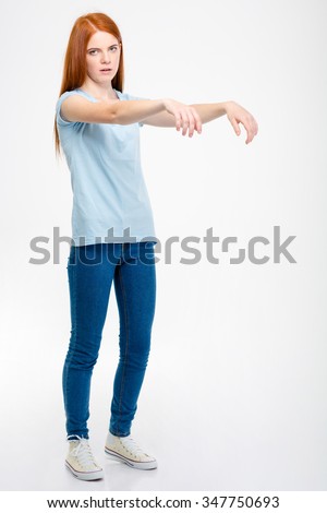 Amusing pretty young woman standing and posing like a zombie isolated over white background