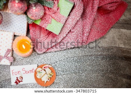Artistic still life with festive spices and fresh colourful fruit lying in a hessian bag on fresh snow against a wooden backdrop with copyspace for your seasonal Christmas greeting
