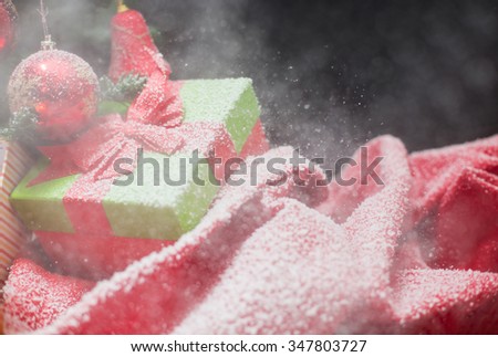 green Christmas gift box with its lid propped at an angle in front to display the beautiful red  ribbon with falling winter snowflakes and copyspace for your greeting or wishes