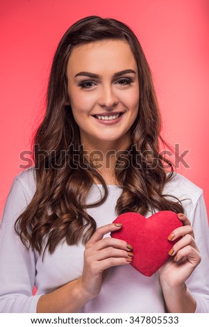 Portrait of a happy young woman in love with heart in hand on a red background