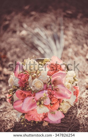 Bridal autumn bouquet with red and white roses over yellow autumn grass. Wedding in fall.