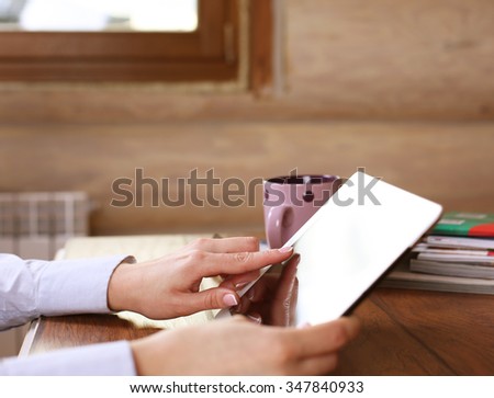 Photo of a woman holding a tablet with no name coffee cup and a tablet