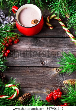 Hot chocolate and Xmas wreath  on wooden background. Christmas ornaments on wood with candy and berries.