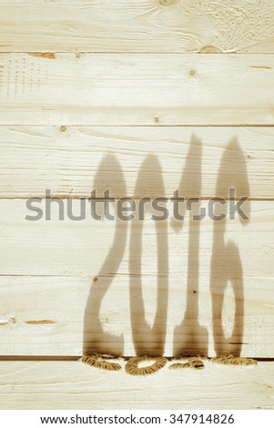 Number two thousand and sixteens shadow falls on the wooden table