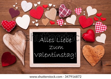 Chalkboard With German Text Alles Liebe Zum Valentinstag Means Happy Valentines Day. Many Red Textile Hearts. Wooden Background With Vintage, Rustic Or Retro Style.