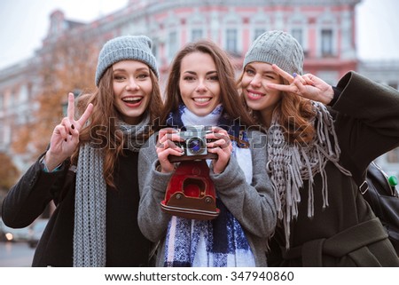 Portrait of a young girlfriends standing with photo camera outdoors