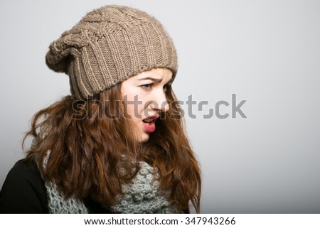 beautiful girl unpleasantly surprised in winter clothes, Christmas and New Year concept shot isolated on gray background