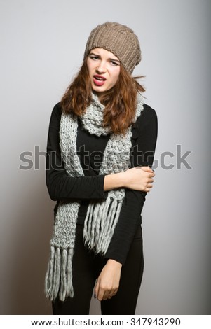 beautiful girl unpleasantly surprised in winter clothes, Christmas and New Year concept shot isolated on gray background