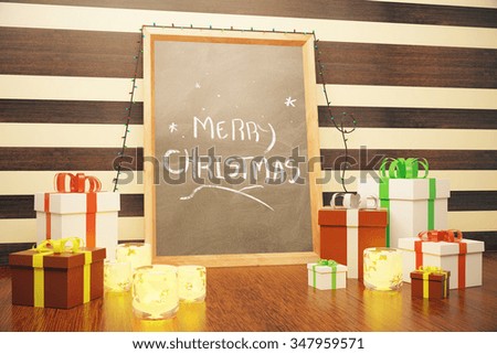 Merry Christmas inscription on picture frame with gift boxes and candlesticks on wooden floor