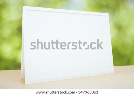 Blank picture frame on the table at foliage background, mock up