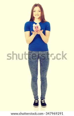 Happy teenage woman holding piggybank.