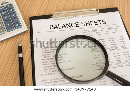 financial statement with magnifier, pen, summary report and calculator on auditor's desk.