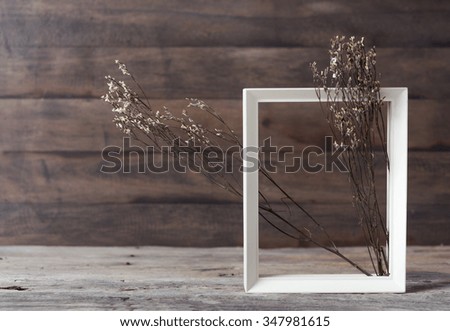 White wooden frame and dry flower on grunge wood background