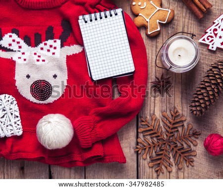 Christmas set. Warm blanket, sweater with a deer, candle, notebook, spices, cinnamon, pine cones, heart  on the wooden background