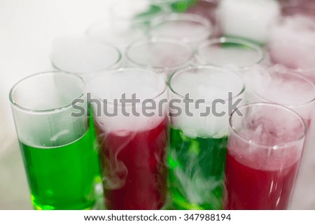 Beautiful row line of red green colored alcohol cocktails with mint on a christmas party, martini, vodka with bubbles, and others on decorated catering bouquet table on open air event, picture 