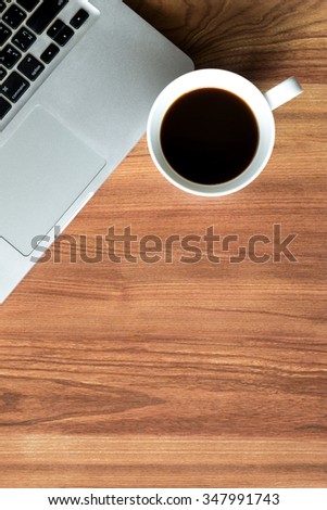 Wood table with laptop and a cup of coffee. Top view with copy space.