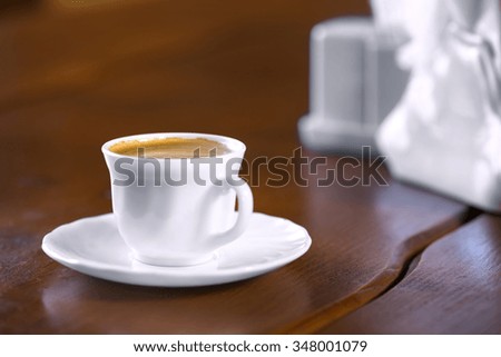 White cup of coffee on wooden table with blurred background