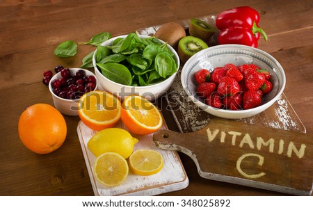 Foods containing vitamin C on a wooden background.