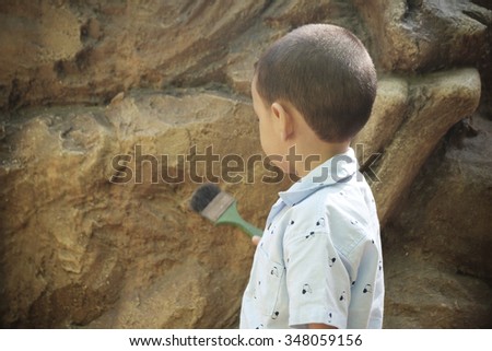 kid playing with brush and stone background , concept for learning by doing , Imagination and dreams concept