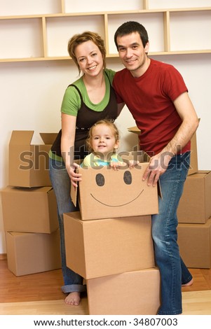 Happy family unpacking in their new home - lots of cardboard boxes all around