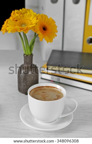 Cup of coffee and flowers on workplace in home or office