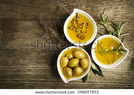 Olive oil with fresh herbs on wooden background. Royalty-Free Stock Photo #348097892