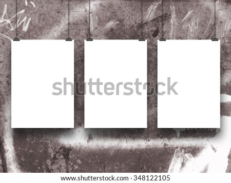 Three hanged paper sheet frames with clips on spray painted wall background