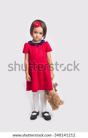 Unhappy beautiful little girl in a red dress with a toy bear Royalty-Free Stock Photo #348141212