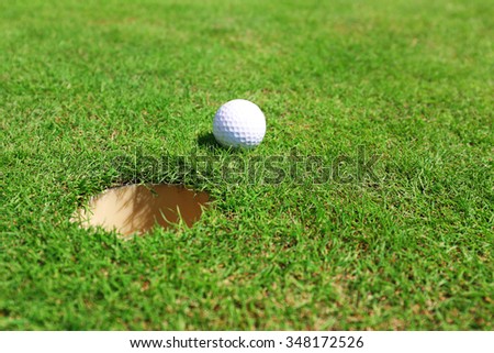 Golf ball on lip of cup on the green golf course