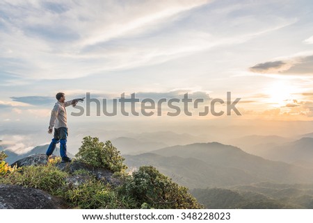 man point his hand to the sun on top of a mountain enjoying valley view Royalty-Free Stock Photo #348228023