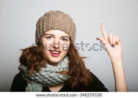 bright girl has a great idea, dressed in winter clothing, Christmas and New Year concept, studio photo isolated on a gray background