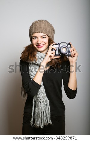 bright photographed a girl on a retro camera, dressed in winter clothing, Christmas and New Year concept, studio photo isolated on a gray background