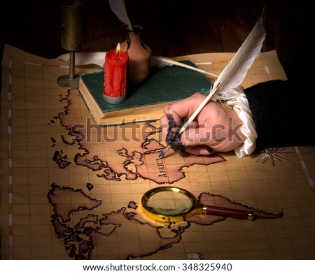 Hand with ink stained fingers draws map of the world ancient quill pen