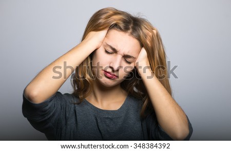 blonde girl has a severe headache, with clean skin, lifestyle concept studio photo isolated on a gray background
