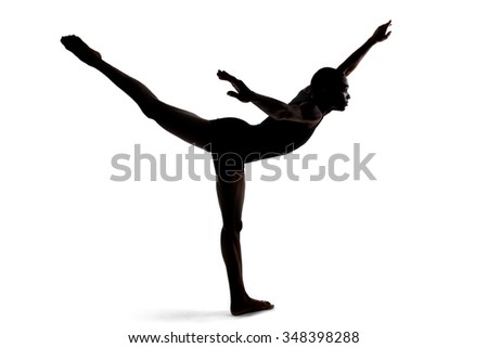 Silhouette of a flexible male dancer posing and balancing on white background.  He is backlit for a shadow silhouette effect. His body forms a letter T.