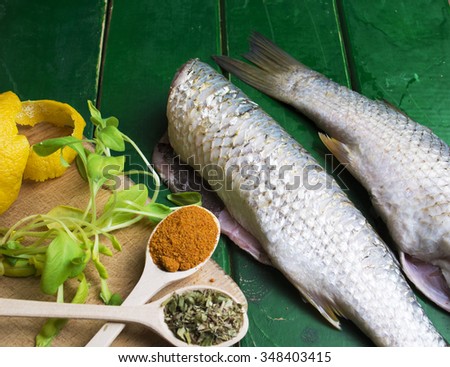 fresh fish on dark vintage green  background. Fish with aromatic herbs, spices and lemon - healthy food, diet or cooking concept. selective focus