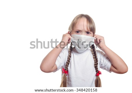 The little girl with long hair puts on a medical mask