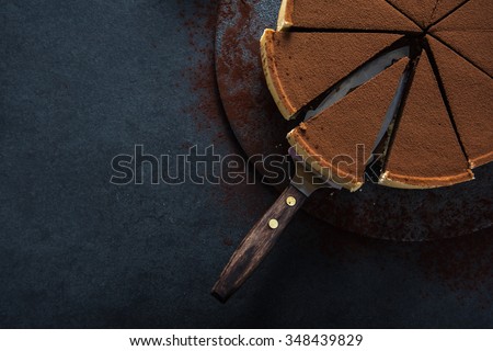 Sliced chocolate tort on dark background, overhead view