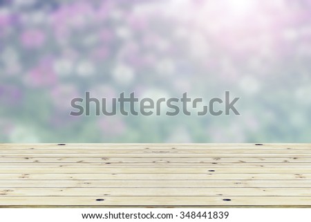 Wood table top on blurred background of pink flowers.