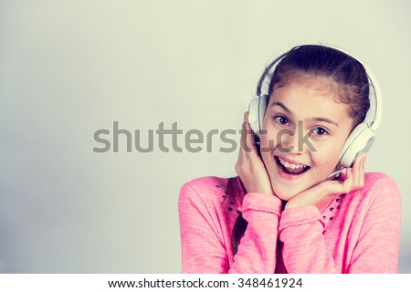 Little girl enjoying music in headphones at home relaxing. Relaxed little girl listening to music with earphones  looking serene and happy.