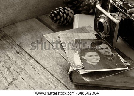 old photo camera, antique photos and old book on wooden table. black and white. selective focus