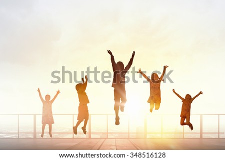 Silhouettes of group of children jumping high joyfully on sunset background
