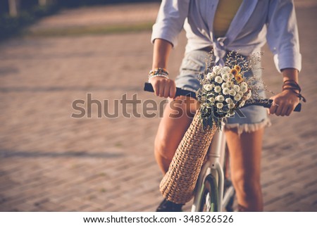 Cropped image of woman riding bicycle with wildflowers in basket
