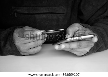 Man holding credit card ans smart phone for shopping online.Black and White effected photo.