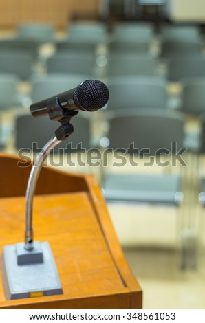 Microphone on the speech podium over the Abstract blurred photo of conference hall or seminar room background