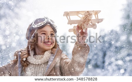 happy child playing with toy plane outdoors in winter