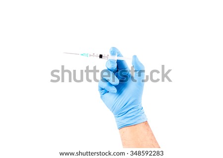 An arm with blue glove holding a syringe to vaccinate